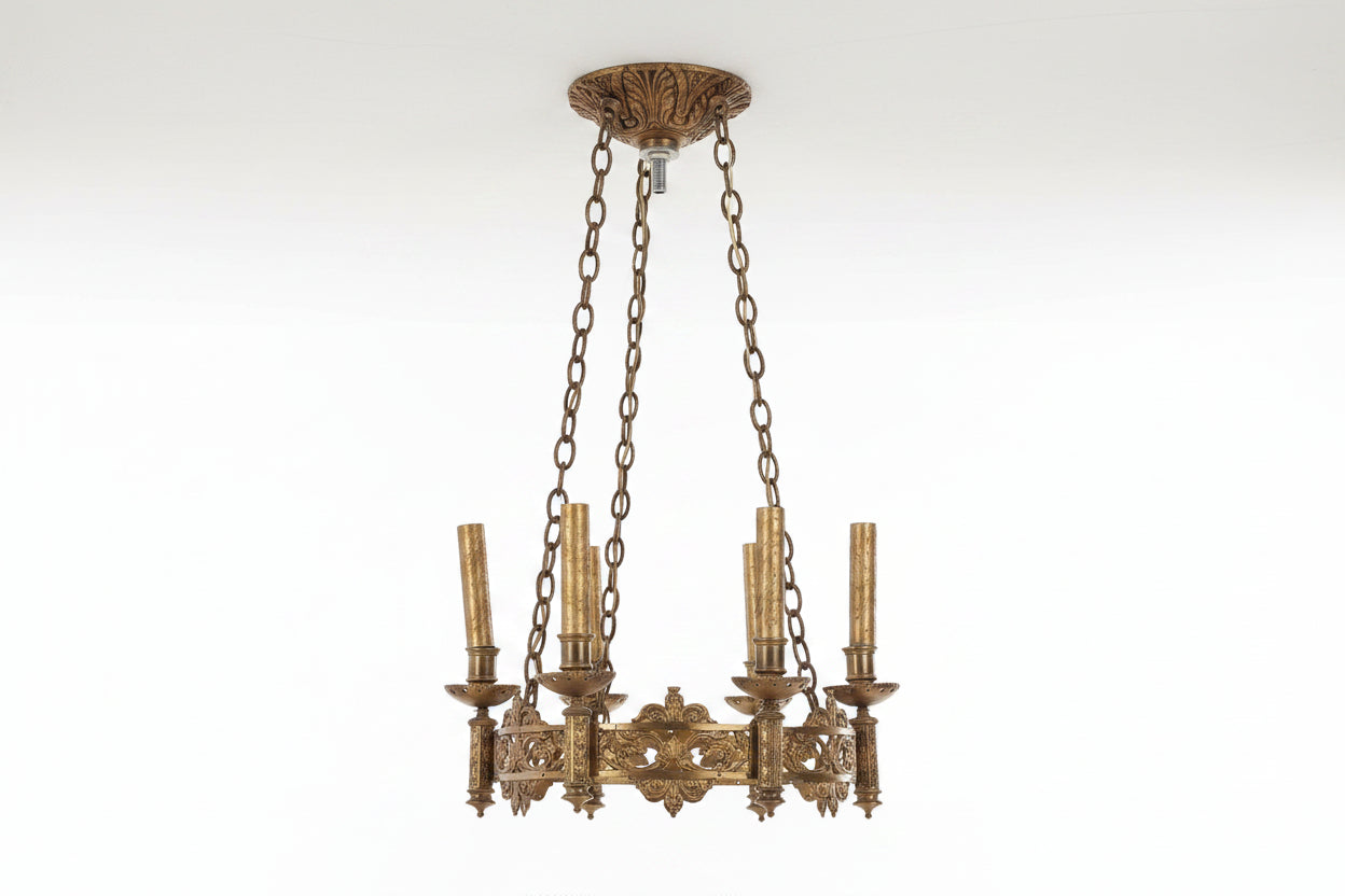 Decorative brass chandelier with intricate designs on a white background