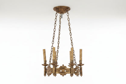Decorative brass chandelier with intricate designs on a white background